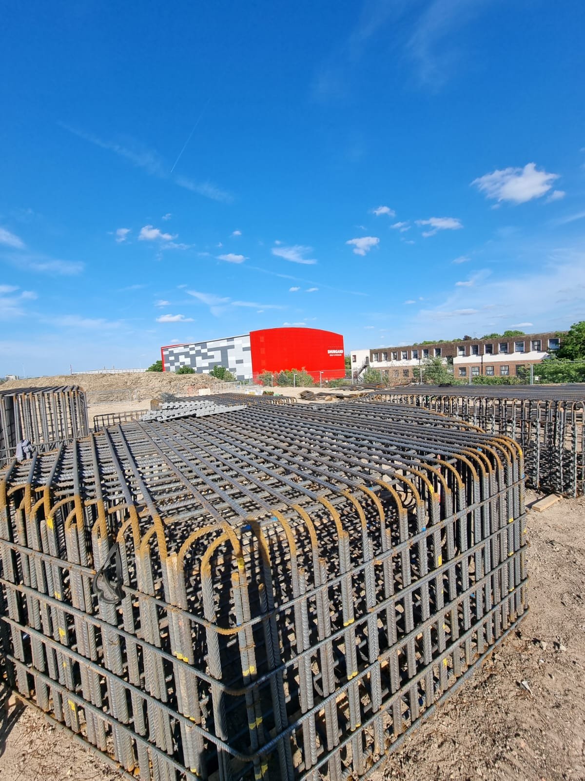 Stacked rebar cages on HS2 site with Shurgard building in background
