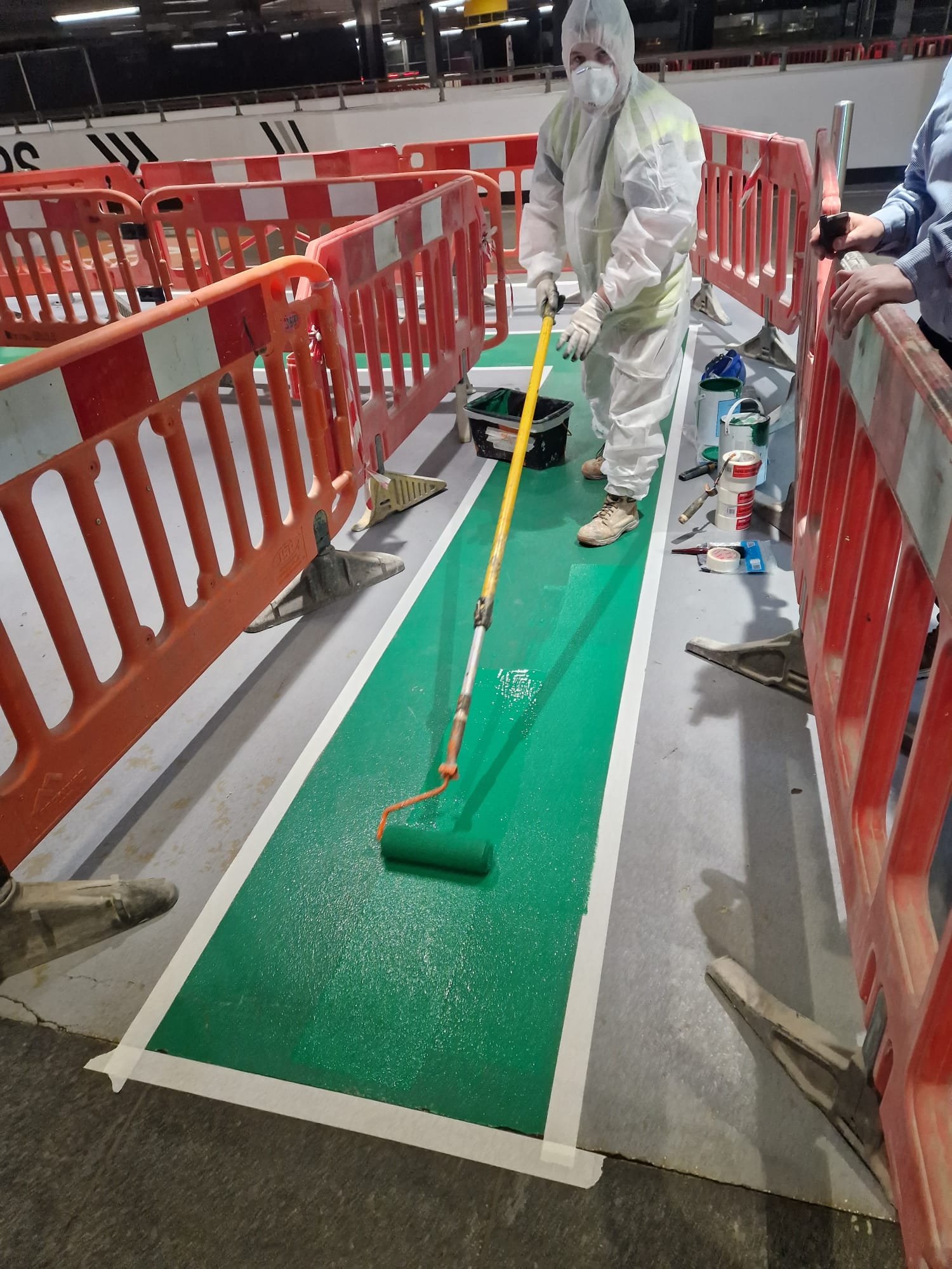 Green walkway being rolled in epoxy paint with masked edges