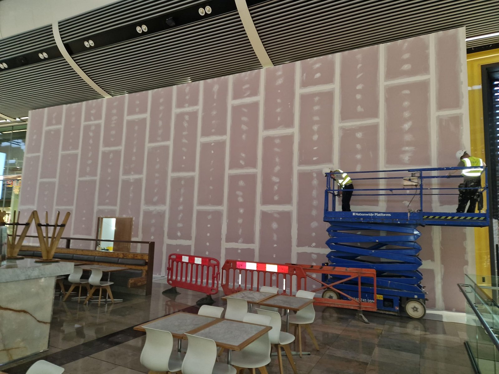 Plasterboard hoarding being finished from MEWP