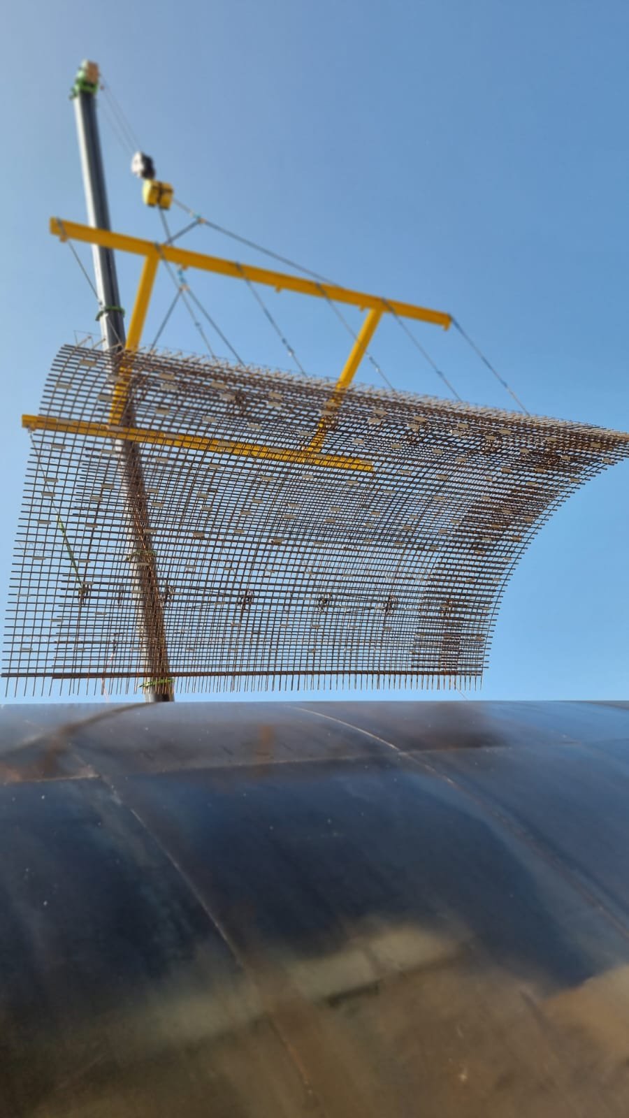 Crane lifting curved rebar panel into position