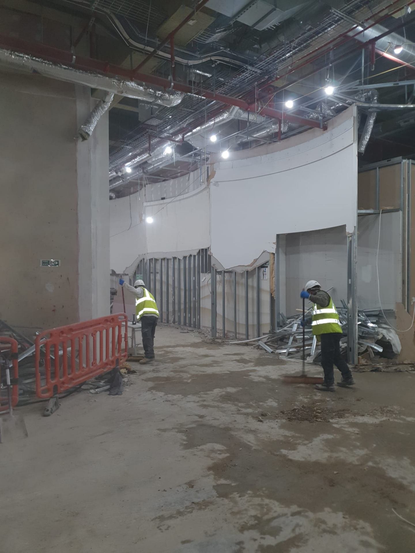 Operatives clearing metal stud framing after wall demolition