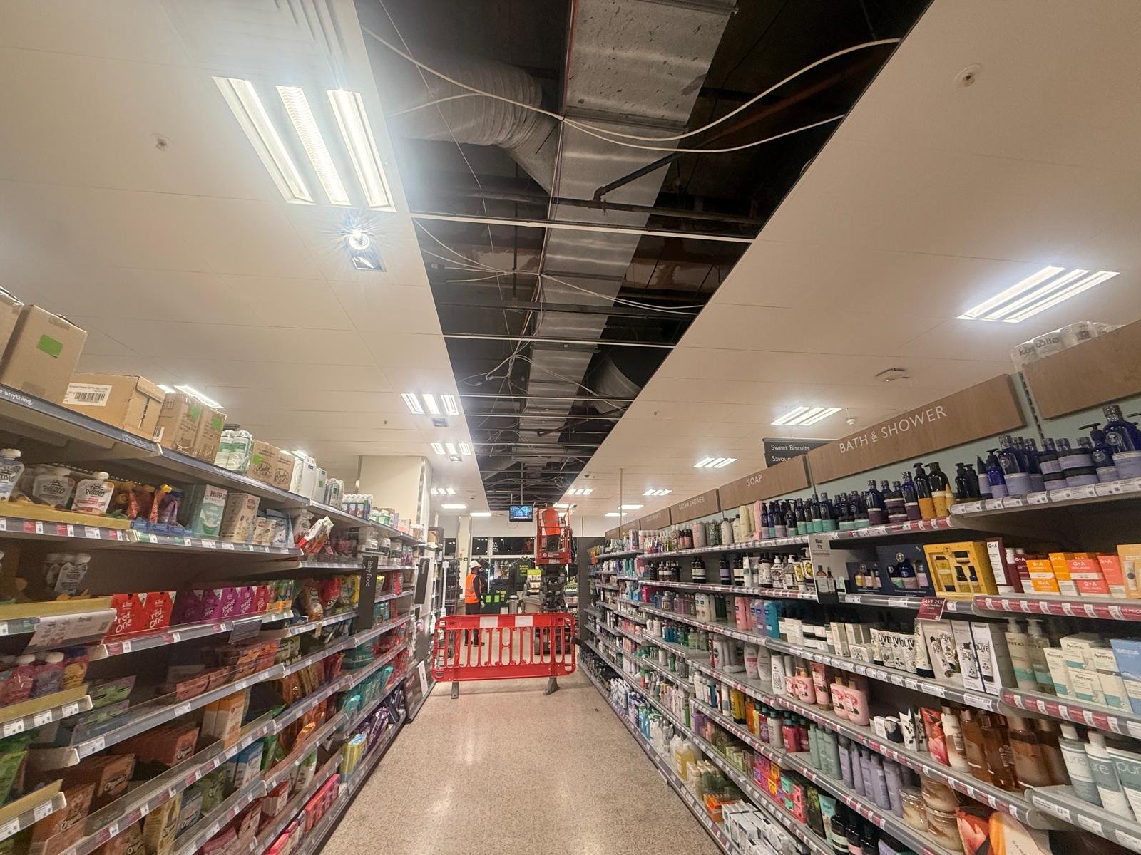 Long run of opened ceiling grid above hosiery and feminine care aisles