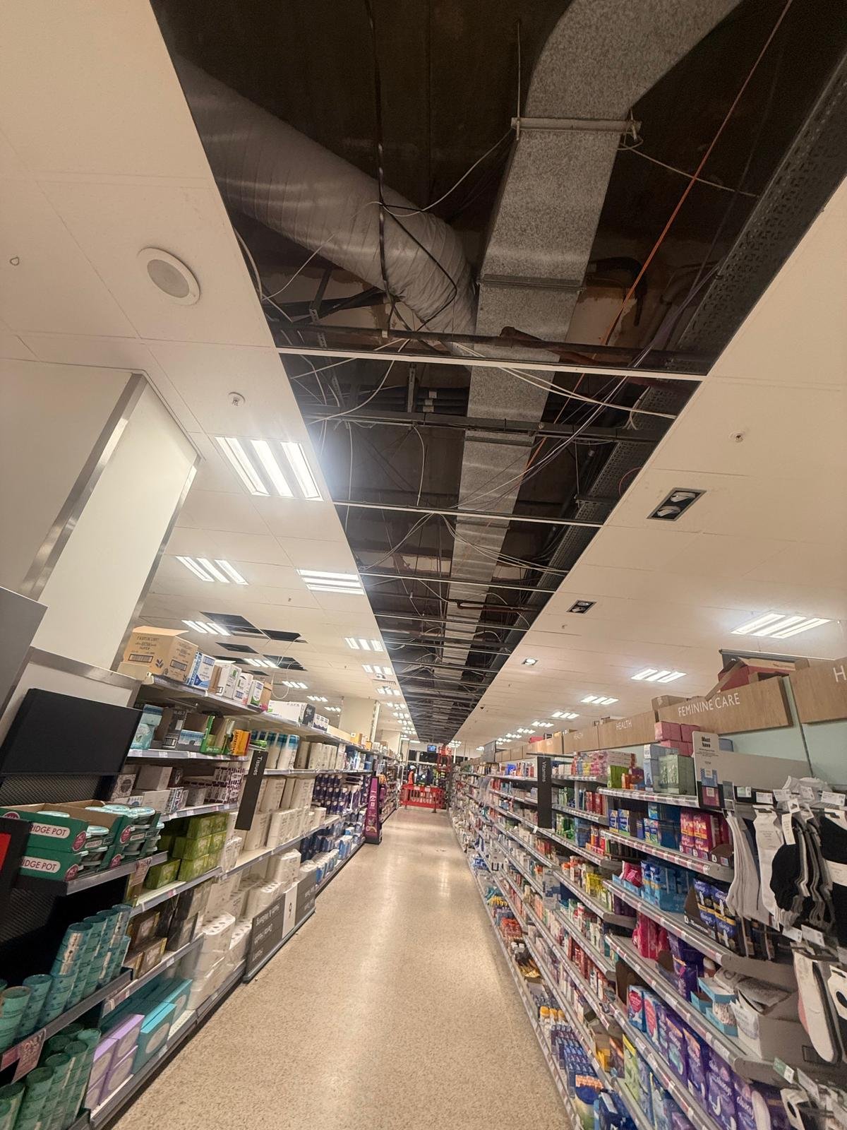 Wide view of stripped ceiling tiles with operative on MEWP